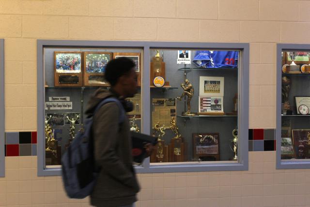 A student walks by an athletics trophy case at Alexandria City High School, where US track and field athlete Noah Lyles graduated from, in Alexandria, Virginia, on August 25, 2025. The trophies line the halls of the small high school which Noah Lyles, the future Olympic 100 metres champion and the man bidding for double gold at the world championships in Tokyo this month, attended. The young Lyles spoke little but took everything in. Lyles began attending Alexandria High School aged 14. His athletic prowess soon became the stuff of legend here. His parents, both high-level college athletes themselves but recently separated, constantly pushed him to do more and go faster and he excelled. (Photo by Paul NOLP / AFP)
