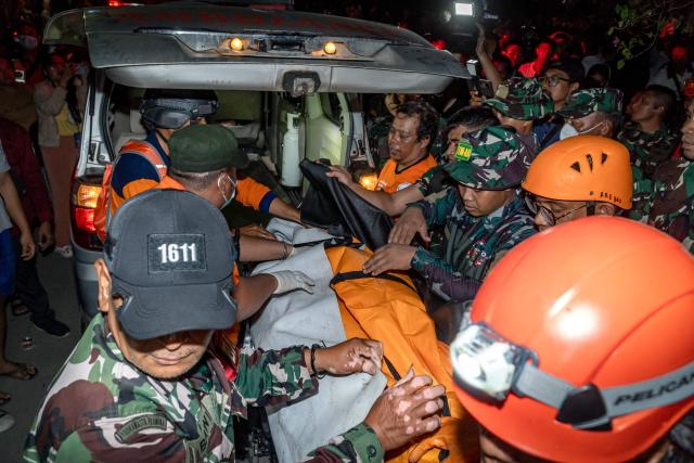 EDITORS NOTE: Graphic content / Rescue team members load a body bag into a vehicle after finding a victim from the debris of a collapsed building in Denpasar, Bali on September 11, 2025, following a flood caused by heavy rain across the island. Torrential rain since late September 9 triggered floods and landslides in seven districts across Bali, National Disaster Mitigation Agency spokesman Abdul Muhari said in a statement. (Photo by Dicky Bisinglasi / AFP)