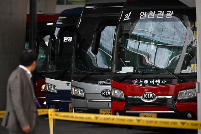 A man walks past coaches parked outside Incheon International Airport in Incheon on September 12, 2025, before the arrival of a specially chartered Korean Air Boeing 747-81 (KE9036) bringing hundreds of South Korean workers back from Atlanta after their detention in a US immigration raid at a Hyundai-LG plant in Ellabell, Georgia. (Photo by Anthony WALLACE / AFP)