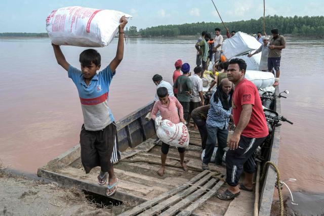 In this photograph taken on September 11, 2025, villagers unload their belongings after crossing the overflowing Ravi River on a boat following heavy monsoon rains in the village of Toor near the Gurdaspur district in India's Punjab state. The fields are full but the paddy brown and wilted, and the air thick with the stench of rotting crops and livestock -- the aftermath of record monsoon rains that have devastated India's breadbasket. (Photo by Narinder NANU / AFP) / To go with 'India-Pakistan-Flood-Climate-Agriculture', FOCUS by Arunabh SAIKIA