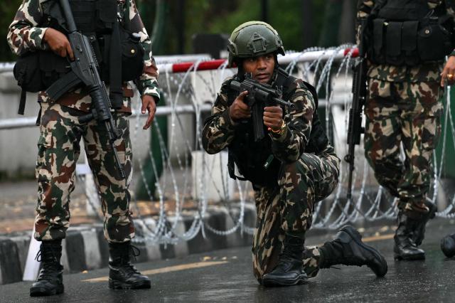 Nepal's army soldier takes his position to disperse the protesters in front of the President House during a curfew imposed to restore law and order, in Kathmandu on September 12, 2025. Nepal's president and army sought on September 12 to find a consensus interim leader to fill a political vacuum after deadly anti-corruption protests toppled the government and left parliament in flames. (Photo by Arun SANKAR / AFP)