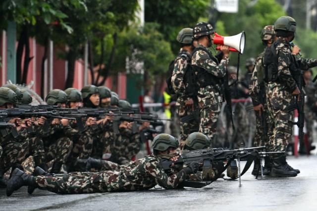 Nepal's army soldiers take their positions to disperse the protesters in front of the President House during a curfew imposed to restore law and order, in Kathmandu on September 12, 2025. Nepal's president and army sought on September 12 to find a consensus interim leader to fill a political vacuum after deadly anti-corruption protests toppled the government and left parliament in flames. (Photo by Arun SANKAR / AFP)