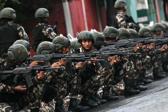 Nepal's army soldiers take their positions to disperse the protesters in front of the President House during a curfew imposed to restore law and order, in Kathmandu on September 12, 2025. Nepal's president and army sought on September 12 to find a consensus interim leader to fill a political vacuum after deadly anti-corruption protests toppled the government and left parliament in flames. (Photo by Arun SANKAR / AFP)