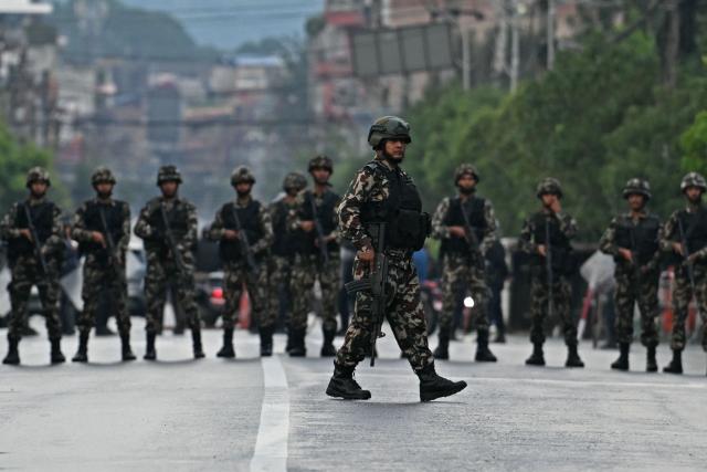 Nepal's army soldiers take their positions to disperse the protesters in front of the President House during a curfew imposed to restore law and order, in Kathmandu on September 12, 2025. Nepal's president and army sought on September 12 to find a consensus interim leader to fill a political vacuum after deadly anti-corruption protests toppled the government and left parliament in flames. (Photo by Arun SANKAR / AFP)