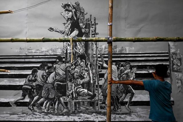 An artist paints a pandal (temporary fabricated structure) ahead of the Durga Puja festival in Kolkata on September 12, 2025. (Photo by DIBYANGSHU SARKAR / AFP)