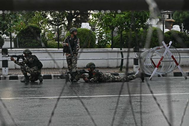 Nepal's army soldiers take their positions to disperse the protesters in front of the President House during a curfew imposed to restore law and order, in Kathmandu on September 12, 2025. Nepal's president and army sought on September 12 to find a consensus interim leader to fill a political vacuum after deadly anti-corruption protests toppled the government and left parliament in flames. (Photo by Arun SANKAR / AFP)