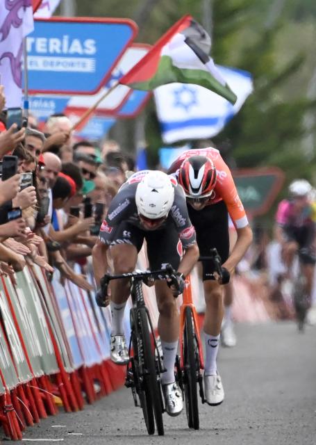 Protestors hold Palestinian and Israel's flags as team Alpecin's Belgian rider Jasper Philipsen competes before the finish line of the 19th stage of the Vuelta a Espana, a 159 km race between Rueda and Guijuelo, on September 12, 2025. (Photo by Miguel RIOPA / AFP)
