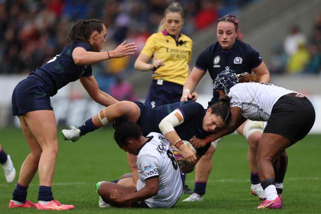 Scotland's center Lisa Thomson (C top) is tackled by Fiji's number 8 Manuqalo Komaitai (C bottom) during the Women’s Rugby World Cup pool B match between Scotland and Fiji at Salford Community Stadium, Manchester, northwest England, on August 30, 2025. (Photo by Adrian Dennis / AFP)