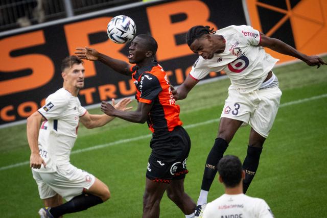 Lorient's Senegalese forward #28 Sambou Soumano (C) fights for the ball with Lille's Belgian defender #03 Nathan Ngoy (R) during the French L1 football match between FC Lorient and lille OSC at Yves-Allainmat stadium in Lorient, western France on August 30, 2025. (Photo by Loic VENANCE / AFP)