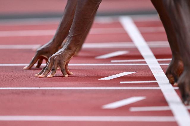 An athlete takes his position at the start line of the men's 100m heats during the World Athletics Championships in Tokyo on September 13, 2025. (Photo by Kirill KUDRYAVTSEV / AFP)