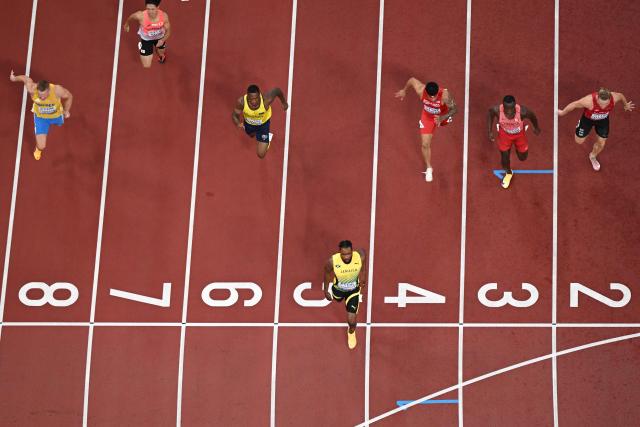 Jamaica's Kishane Thompson (C) crosses the finish line as he competes in the men's 100m heats during the World Athletics Championships in Tokyo on September 13, 2025. (Photo by Jewel SAMAD / AFP)
