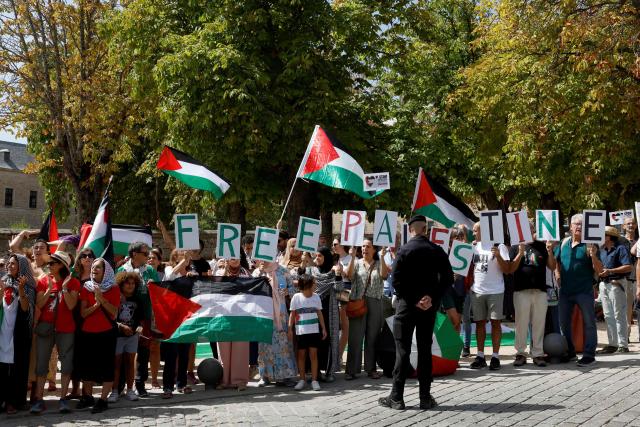 Guardia Civil officers stand as Pro-Palestinians protesters hold Palestinian flags and letters reading 'Free Palestine' during the 20th stage of the Vuelta a Espana 2025, a 156 km race between Robledo de Chavela and Bola del Mundo, in El Escorial, on September 13, 2025. (Photo by Pierre-Philippe MARCOU / AFP)