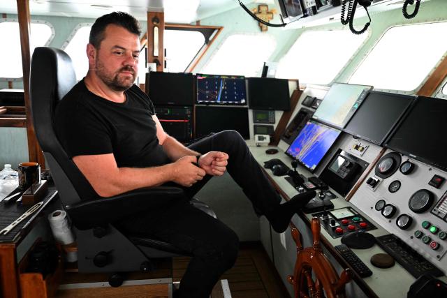 Nicolas Margolle, captain of the trawler "Nicolas-Jeremy", which practices pair trawling in tandem with the "Notre Dame de Boulogne" trawler, sits at the helm of his boat during a sardine fishing campaign, off the Baie de Somme of northern France, on September 8, 2025. Between regulations, the creation of non-fishing zones, licenses to access to British waters and possible competition from some North Sea countries, the captain of the "Nicolas-Jeremy" fears his generation could the last of a long line of fishermen. (Photo by FRANCOIS NASCIMBENI / AFP)