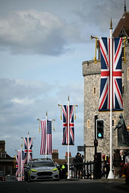 A police car drives past US and Union Jack flags flying from poles outside Windsor Castle in Windsor, on September 16, 2025, on the eve of a State Visit by the US President and the First Lady. Donald Trump lands in Britain on Tuesday for an historic second state visit that will see the UK government spare no effort in trying to flatter the mercurial American president. (Photo by JUSTIN TALLIS / AFP)