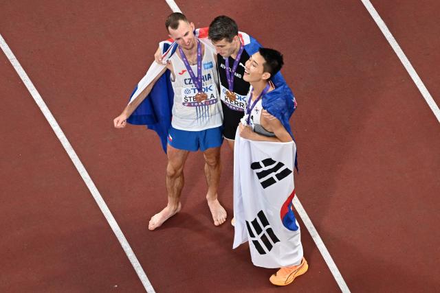 (L-R) Bronze medallist Czech Republic's athlete Jan Stefela, Gold medallist New Zealand's athlete Hamish Kerr and silver medallist South Korea's Sanghyeok Woo celebrate after the men's high jump final during the World Athletics Championships in Tokyo on September 16, 2025. (Photo by Antonin THUILLIER / AFP)