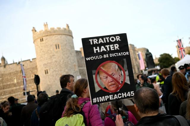 A demonstrator holds a placard during a protest against the forthcoming State Visit of US President Donald Trump, outside Windsor Castle in Windsor on September 16, 2025. US President Donald Trump is set arrive in the UK late September 16, 2025 for a second State Visit with his wife Melania, made at the invitation of King Charles III. (Photo by JUSTIN TALLIS / AFP)