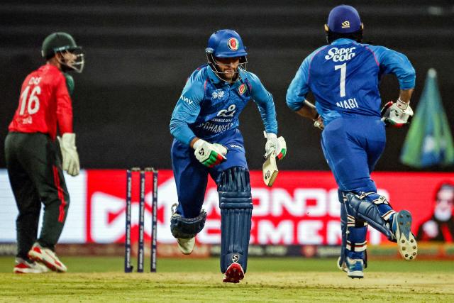 Afghanistan's Azmatullah Omarzai (C) and Mohammad Nabi run between the wickets during the Asia Cup 2025 Twenty20 international cricket match between Afghanistan and Bangladesh at the Sheikh Zayed Cricket Stadium in Abu Dhabi on September 16, 2025. (Photo by Fadel SENNA / AFP)