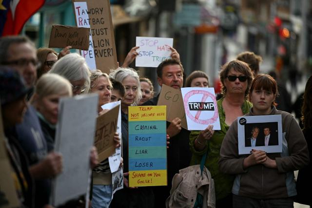 Demonstrators hold placards during a protest against the forthcoming State Visit of US President Donald Trump, outside Windsor Castle in Windsor on September 16, 2025. US President Donald Trump is set arrive in the UK late September 16, 2025 for a second State Visit with his wife Melania, made at the invitation of King Charles III. (Photo by JUSTIN TALLIS / AFP)