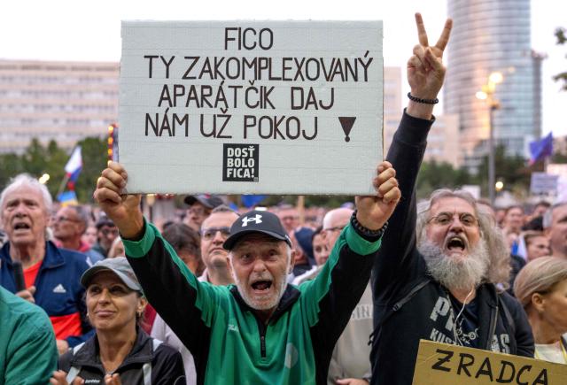 Participants hold up a placard reading 'Fico you complexed Apparatchik leave us alone' while protesting against the government's proposed cost-cutting measures during a rally against nationalist premier Fico in Bratislava on September 16, 2025. Since his return to power in 2023, Fico has faced a series of protests over his curbing of rights and seeking close ties with Russian President Putin. Thousands of Slovaks gathered in front of the government's main office building in Bratislava, shouting "Enough of Fico! Fico go to jail!" and "It is enough. We are fed up!" The protest was called by the opposition, with organisers estimating up to 18,000 people attended. (Photo by Joe Klamar / AFP)