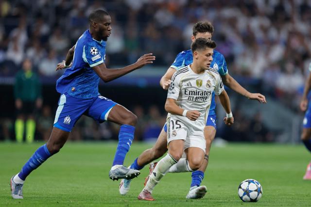 Real Madrid's Turkish midfielder #15 Arda Guler (R) runs with the ball challenged by Marseille's Central midfielder #19 Geoffrey Kondogbia during the UEFA Champions League first round day 1 football match between Real Madrid CF and Olympique de Marseille at the Santiago Bernabeu stadium in Madrid on September 16, 2025. (Photo by Oscar DEL POZO / AFP)