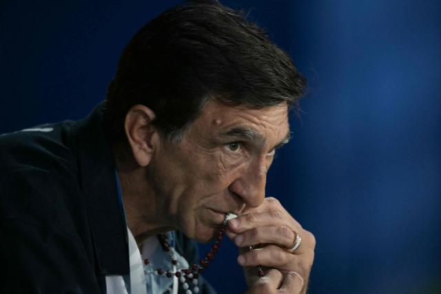 TOPSHOT - Racing's head coach Gustavo Costas kisses his rosary during the Copa Libertadores quarterfinal first leg all-Argentine football match between Velez Sarsfield and Racing at the Jose Amalfitani Stadium in Buenos Aires on September 16, 2025. (Photo by JUAN MABROMATA / AFP)