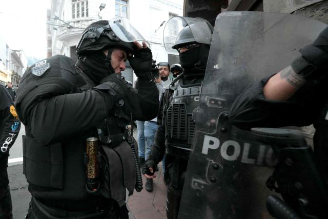 An Ecuadorian riot police officer gestures during a protest against President Daniel Noboa's cuts and the elimination of diesel subsidy within a state of emergency declared by the government in Quito on September 16, 2025. (Photo by Rodrigo BUENDIA / AFP)