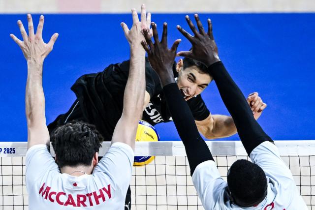 TOPSHOT - Turkey's Ramazan Efe Mandiraci spikes the ball against Canada's Fynnian Lionel (L) and Sharone Vernon-Evans (R) during the 2025 Men's Volleyball World Championship at Araneta Coliseum in Quezon City, metro Manila on September 17, 2025. (Photo by SHERWIN VARDELEON / AFP)