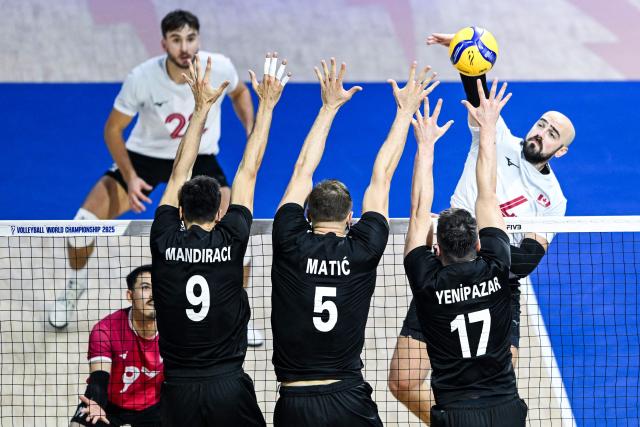 Canada's Nicholas Hoag spikes the ball above Turkey's Ramazan Efe Mandiraci, Marko Matic and Murat Yenipazar during the 2025 Men's Volleyball World Championship at Araneta Coliseum in Quezon City, metro Manila on September 17, 2025. (Photo by SHERWIN VARDELEON / AFP)