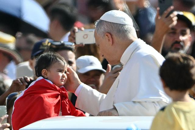 Pope Leo XIV caresses a toddler as he arrives in the Pope Mobile to lead his weekly general audience at St. Peter’s square in the Vatican, on September 17, 2025. (Photo by Alberto PIZZOLI / AFP)