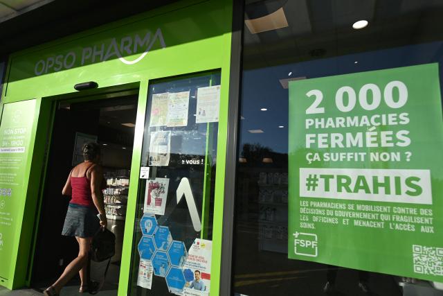 A person enters a drugstore/pharmacy next to a sign reading "2000 Pharmacies closed, that's enough, right? - Betrayed" in Illiers-Combray, western France, on September 17, 2025 on the eve of a national day of blockade. Pharmacies will also join forces on September 18, 2025: about nine out of ten will keep their shutters down to protest the reduction of commercial discounts on generics, a measure aimed at reducing health expenses but deemed catastrophic by the profession. (Photo by JEAN-FRANCOIS MONIER / AFP)