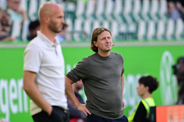 Mainz' Danish head coach Bo Henriksen (R) follows the action from the sidelines behind Wolfsburg's Dutch head coach Paul Simonis during the German first division Bundesliga football match between VfL Wolfsburg and Mainz 05 in Wolfsburg, northern Germany on August 31, 2025. (Photo by Tobias SCHWARZ / AFP) / DFL REGULATIONS PROHIBIT ANY USE OF PHOTOGRAPHS AS IMAGE SEQUENCES AND/OR QUASI-VIDEO