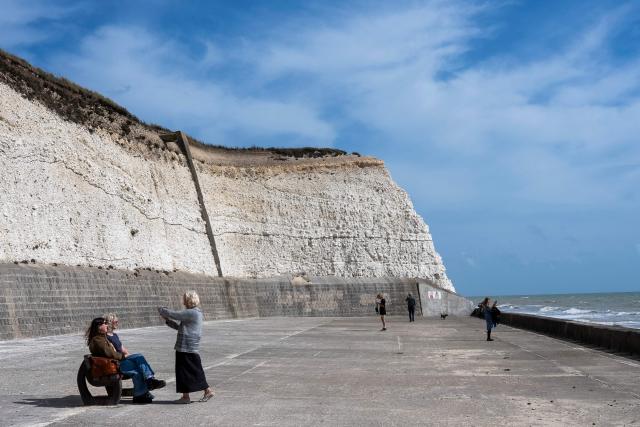 People walk in the sunshine along the Undercliff Walk at Saltdean Cliffs in Brighton, on the south coast of England on August 31, 2025. (Photo by CARLOS JASSO / AFP)
