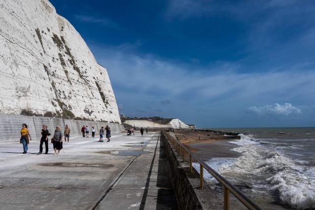 People walk in the sunshine along the Undercliff Walk at Saltdean Cliffs in Brighton, on the south coast of England on August 31, 2025. (Photo by CARLOS JASSO / AFP)