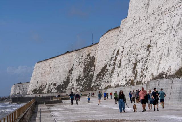 People walk in the sunshine along the Undercliff Walk at Saltdean Cliffs in Brighton, on the south coast of England on August 31, 2025. (Photo by CARLOS JASSO / AFP)