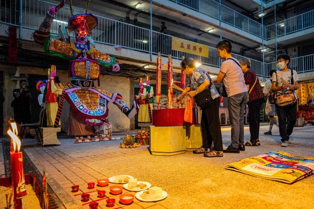 People offer prayers during the Hungry Ghost or the Yu Lan festival at the Wah Fu Estate in Hong Kong on August 31, 2025. Eyes glowing red, the towering "ghost king" presided over the atrium of a Hong Kong housing block on August 31, as residents performed age-old rituals -- a scene that may become history as redevelopment looms. (Photo by Leung Man Hei / AFP)