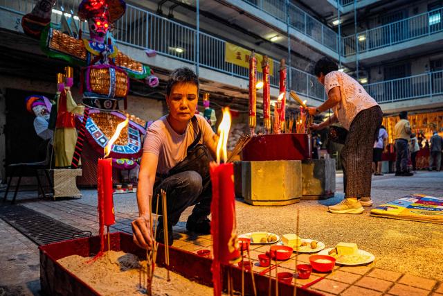 People offer prayers during the Hungry Ghost or the Yu Lan festival at the Wah Fu Estate in Hong Kong on August 31, 2025. Eyes glowing red, the towering "ghost king" presided over the atrium of a Hong Kong housing block on August 31, as residents performed age-old rituals -- a scene that may become history as redevelopment looms. (Photo by Leung Man Hei / AFP)