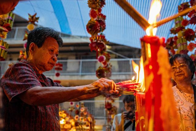 People offer prayers during the Hungry Ghost or the Yu Lan festival at the Wah Fu Estate in Hong Kong on August 31, 2025. Eyes glowing red, the towering "ghost king" presided over the atrium of a Hong Kong housing block on August 31, as residents performed age-old rituals -- a scene that may become history as redevelopment looms. (Photo by Leung Man Hei / AFP)