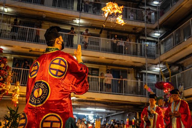 Taoist priests perform the 'Breaking the Hell's Gate' ritual during the Hungry Ghost or the Yu Lan festival at the Wah Fu Estate in Hong Kong on August 31, 2025. Eyes glowing red, the towering "ghost king" presided over the atrium of a Hong Kong housing block on August 31, as residents performed age-old rituals -- a scene that may become history as redevelopment looms. (Photo by Leung Man Hei / AFP)
