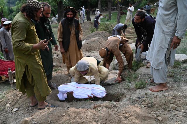 EDITORS NOTE: Graphic content / Afghan men places a body in a shroud in a grave following earthquakes in the Mazar Dara village of Nurgal, a district of the Kunar Province, in Eastern Afghanistan, on September 1, 2025. More than 800 people have died and over 2,700 were injured from August 31 night to September 1, 2025, in eastern Afghanistan after a 6-magnitude earthquake, followed by at least five aftershocks felt hundreds of kilometers away. (Photo by Wakil Kohsar / AFP)