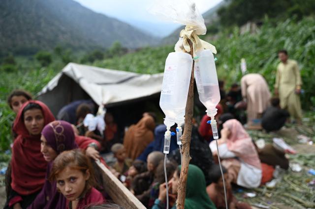 Afghan injured women and girls look on as they recieve treatment, with intravenous drips in the foreground at a field following earthquakes in the Mazar Dara village of Nurgal, a district of the Kunar Province, in Eastern Afghanistan, on September 1, 2025. More than 800 people have died and over 2,700 were injured from August 31 night to September 1, 2025, in eastern Afghanistan after a 6-magnitude earthquake, followed by at least five aftershocks felt hundreds of kilometers away. (Photo by Wakil Kohsar / AFP)