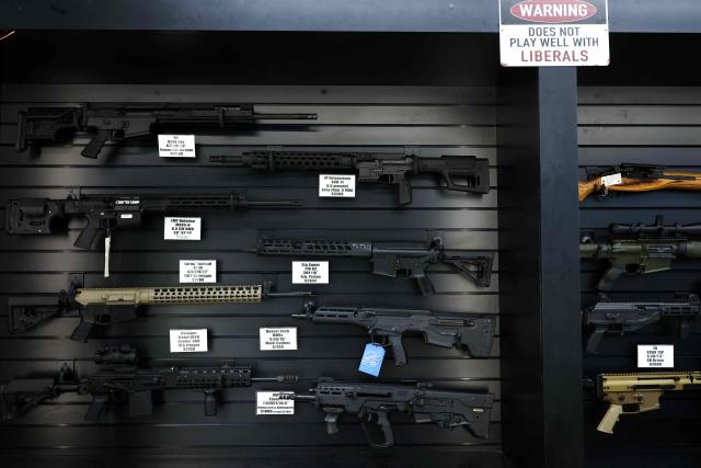 A sign reading "Warning, does not play well with liberals" is seen above semi-automatic rifles displayed for sale in a gun store in Rio Rico, Santa Cruz County, Arizona on September 17, 2025. Arizona allows individuals legally eligible to own guns to carry them without a permit, background checks apply to dealer sales but not most private transactions. (Photo by CHARLY TRIBALLEAU / AFP)