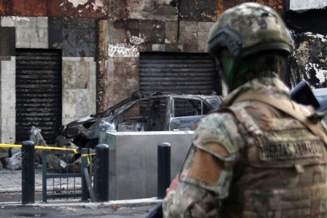 An Ecuadorean army soldier stands guard at the crime scene where a car bomb exploded outside the 'El Boricua' discotheque in Guayaquil, Ecuador on September 17, 2025. (Photo by Gerardo MENOSCAL / AFP)