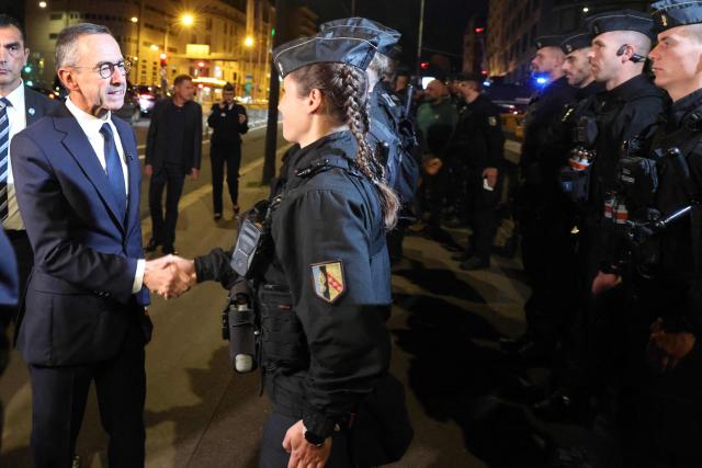 France's Minister of the Interior Bruno Retailleau (L) shakes hands with a female police officer at Porte d'Orléans in Paris on September 18, 2025, prior to a day of nationwide strikes and protests called by unions over France's national budget. France is bracing for a day of nationwide protests on September 18, 2025, with a source close to the authorities saying some 800,000 people are expected to take to the streets. In a rare show of unity, trade unions have urged French people to strike in protest at the authorities' "horror show" draft budget designed to reduce France's ballooning debt. (Photo by Ludovic MARIN / AFP)