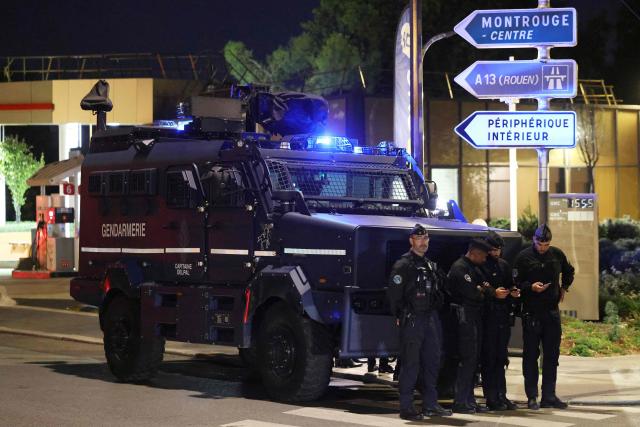 French police officers stand guard in front of a police Centaur vehicle at Porte d'Orléans in Paris on September 18, 2025, prior to a day of nationwide strikes and protests called by unions over France's national budget. France is bracing for a day of nationwide protests on September 18, 2025, with a source close to the authorities saying some 800,000 people are expected to take to the streets. In a rare show of unity, trade unions have urged French people to strike in protest at the authorities' "horror show" draft budget designed to reduce France's ballooning debt. (Photo by Ludovic MARIN / AFP)