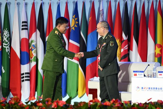 Myanmar’s Defence Minister General Maung Maung Aye (L) shakes hands with General Nie Songlai, Research Fellow, Institute of War Studies at the PLA Academy of Military Sciences, after speaking during a plenary session of the Xiangshan Forum at the Beijing International Convention Center in Beijing on September 18, 2025. (Photo by GREG BAKER / AFP)
