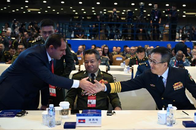 China's Defence Minister Dong Jun (R) shakes hands with Armenia’s Defence Minister Suren Papikyan (L) as Cambodia’s Defence Minister Tea Seiha (C) looks on as they take their seats for the opening ceremony of the Xiangshan Forum at the Beijing International Convention Center in Beijing on September 18, 2025. (Photo by GREG BAKER / AFP)
