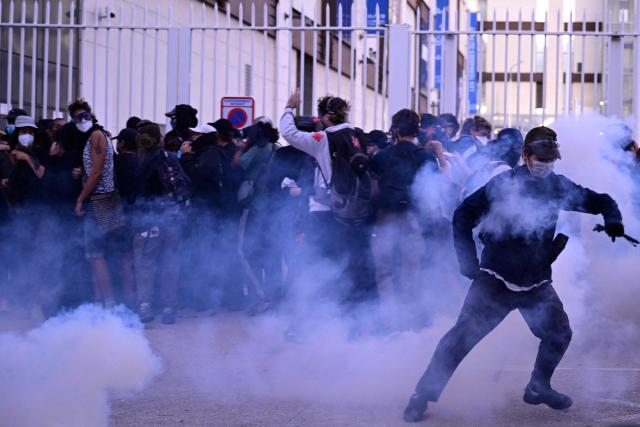 Protesters stand amid clouds of tear gas as they gather for a road blocage in Marseille, southeastern France, on September 18, 2025, as part of a day of nationwide strikes and protests called by unions over France's national budget. France is bracing for a day of nationwide protests on September 18, 2025, with a source close to the authorities saying some 800,000 people are expected to take to the streets. In a rare show of unity, trade unions have urged French people to strike in protest at the authorities' "horror show" draft budget designed to reduce France's ballooning debt. (Photo by Miguel MEDINA / AFP)