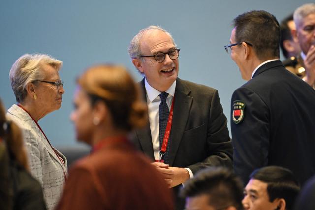 China's Defence Minister Dong Jun (R) shakes hands with Chairman of the Institute for East-West Strategic Studies Baron von Pfetten (C) and French politician Michele Alliot-Marie (L) at the end of the opening ceremony of the Xiangshan Forum at the Beijing International Convention Center in Beijing on September 18, 2025. (Photo by GREG BAKER / AFP)