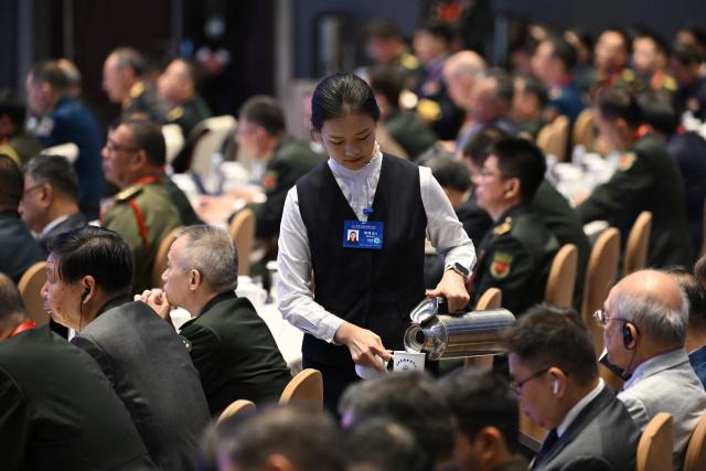 An attendant pours tea for delegates during a plenary session of the Xiangshan Forum at the Beijing International Convention Center in Beijing on September 18, 2025. (Photo by GREG BAKER / AFP)