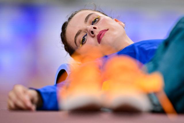 Ukraine's athlete Yaroslava Mahuchikh rests wearing eye make up in the colours of the Ukrainan flag as she waits to compete in the women's high jump qualification during the World Athletics Championships in Tokyo on September 18, 2025. (Photo by Ben STANSALL / AFP)